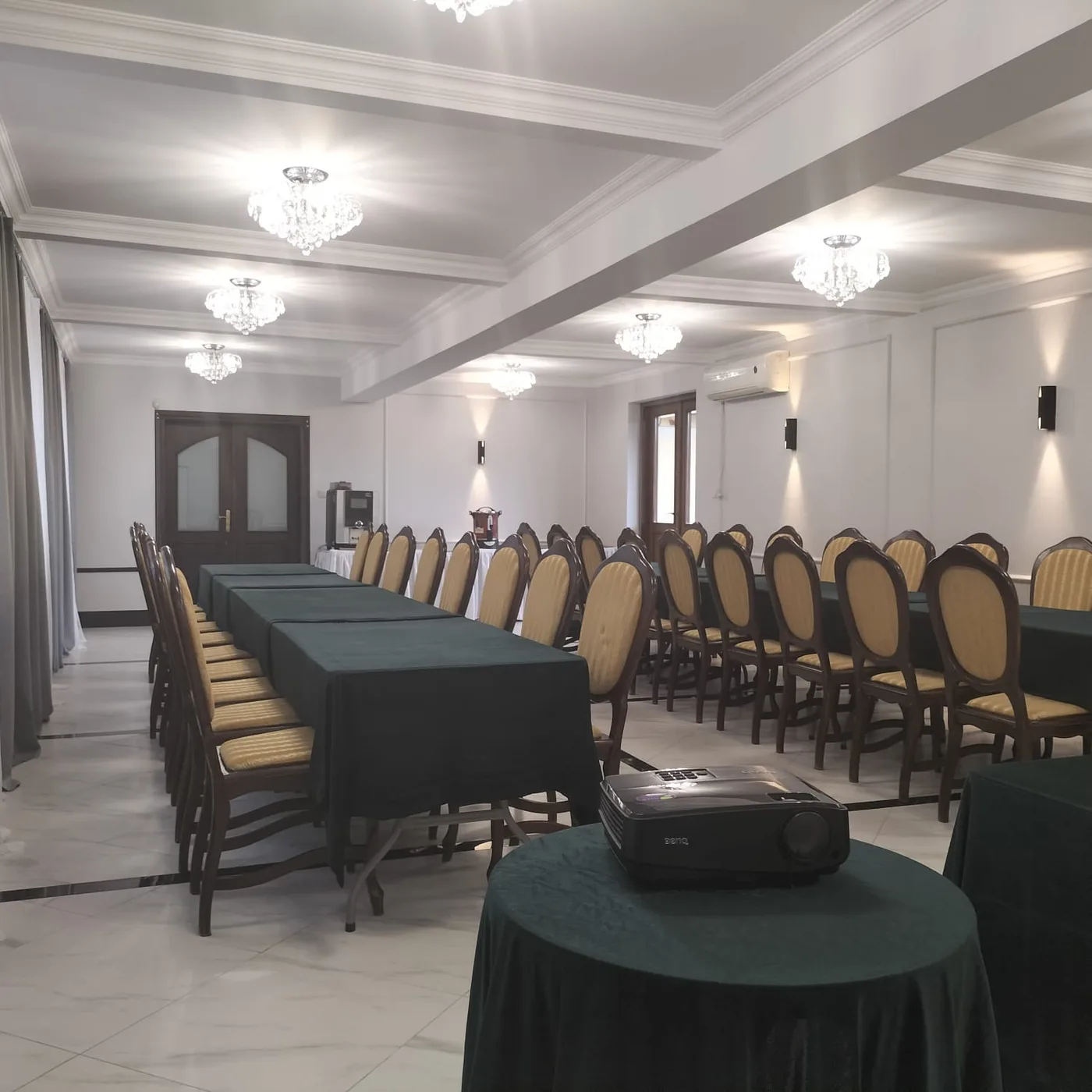 Sala konferencyjna z rzutnikiem na pierwszym planie i bufetem kawowym